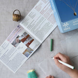 A close up of a child's hand decorating the silk paper squares with felt tip. The kit contains papers, thread and a mini basket. Kraul offers a range of thoughtful science toys that bring natural forces to life through real-world exploration and play.