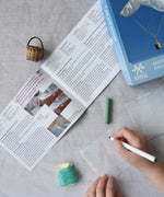 A close up of a child's hand decorating the silk paper squares with felt tip. The kit contains papers, thread and a mini basket. Kraul offers a range of thoughtful science toys that bring natural forces to life through real-world exploration and play.