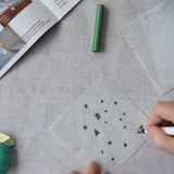 A close up of a child's hand decorating the silk paper squares with felt tip. The kit contains papers, thread and a mini basket. Kraul offers a range of thoughtful science toys that bring natural forces to life through real-world exploration and play.