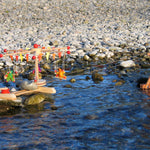 Kraul Wooden Swing Roundabout Kit with passenger dolls in a river