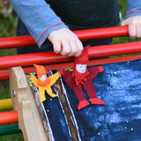 A small and large Kraul tumbling gnome placed on a Triclimb Miri slide covered by a Wonderie play cloth. A child's hand can be seen starting to push the large gnome. 