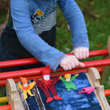 4 Kraul tumbling gnomes placed on a TriClimb Miri slide ready to be tumbled down. A child has pushed a pink coloured gome and it can be seen tumbling down in motion. These felt gnome dolls come in various colours and sizes.