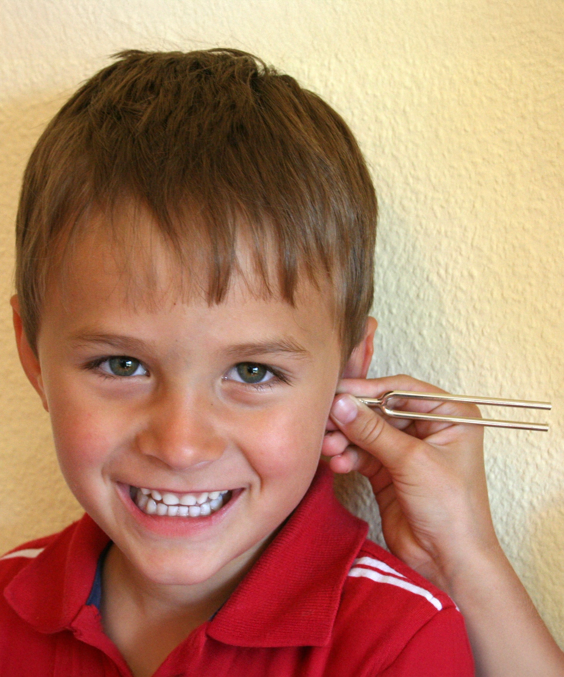 A tuning fork from the Kraul listening kit held next to a child's ear