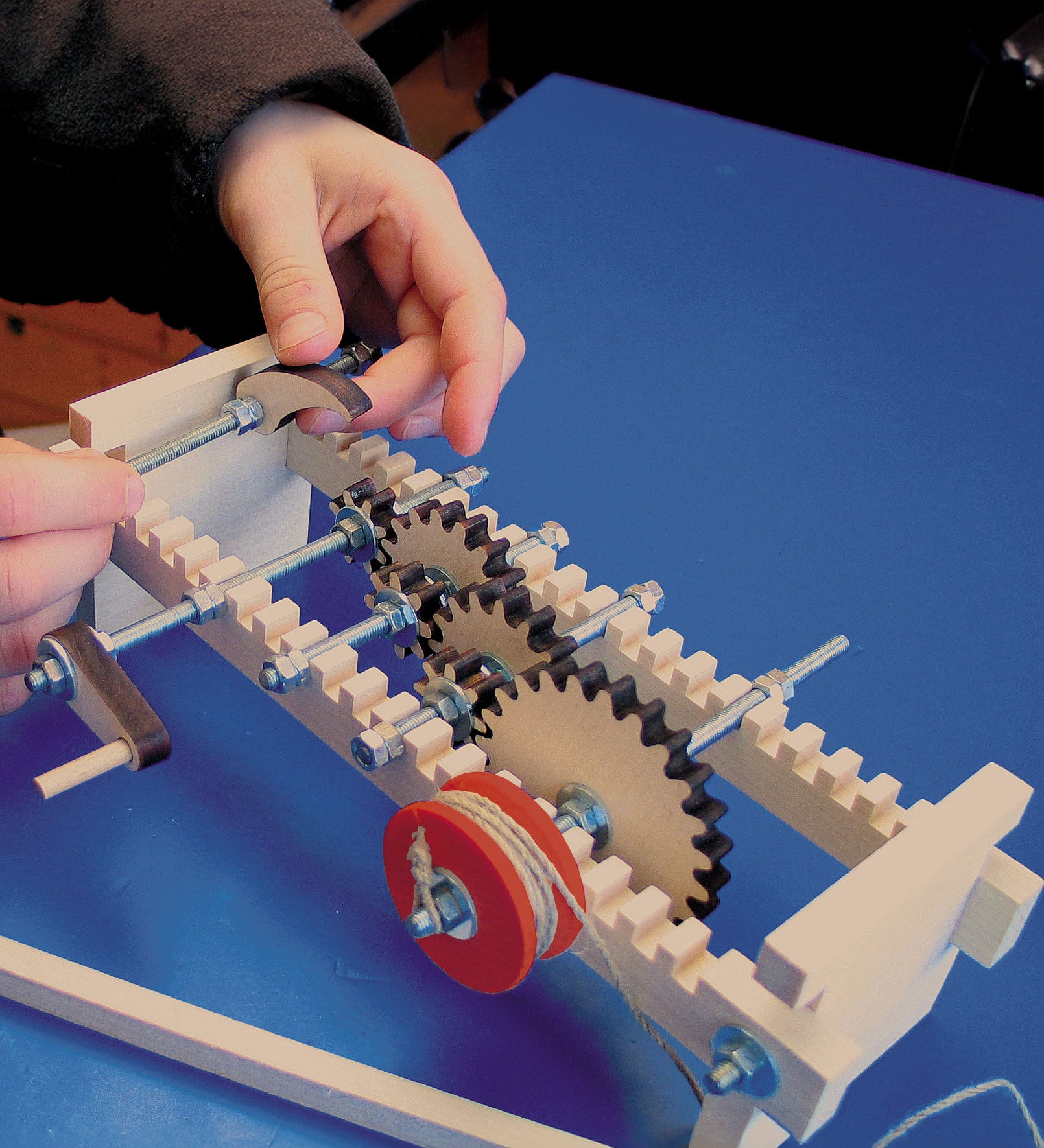 A child using the Kraul Gearwheels wooden cog wheels Experiment Kit whis has been assembled. Discover a world of wonder with Kraul STEM science kits and educational toys available at Babipur.