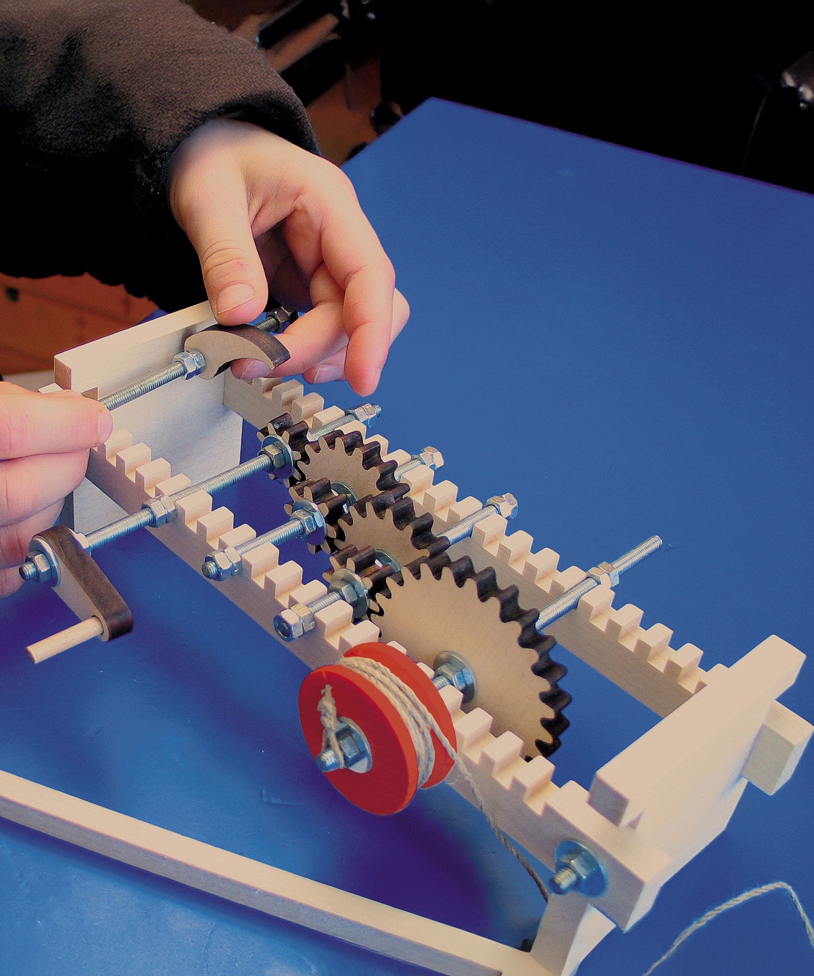 A child using the Kraul Gearwheels wooden cog wheels Experiment Kit whis has been assembled. Discover a world of wonder with Kraul STEM science kits and educational toys available at Babipur.