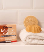 Lamazuna Keratin Repair Shampoo Bar and Keratin Shine Conditioner Bar displayed on a white towel beside their boxes, showing zero waste solid haircare for damaged hair.
