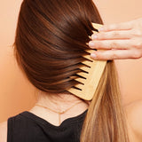 Woman combing long, shiny hair with a wooden comb after using Lamazuna keratin solid haircare for repair and strength.