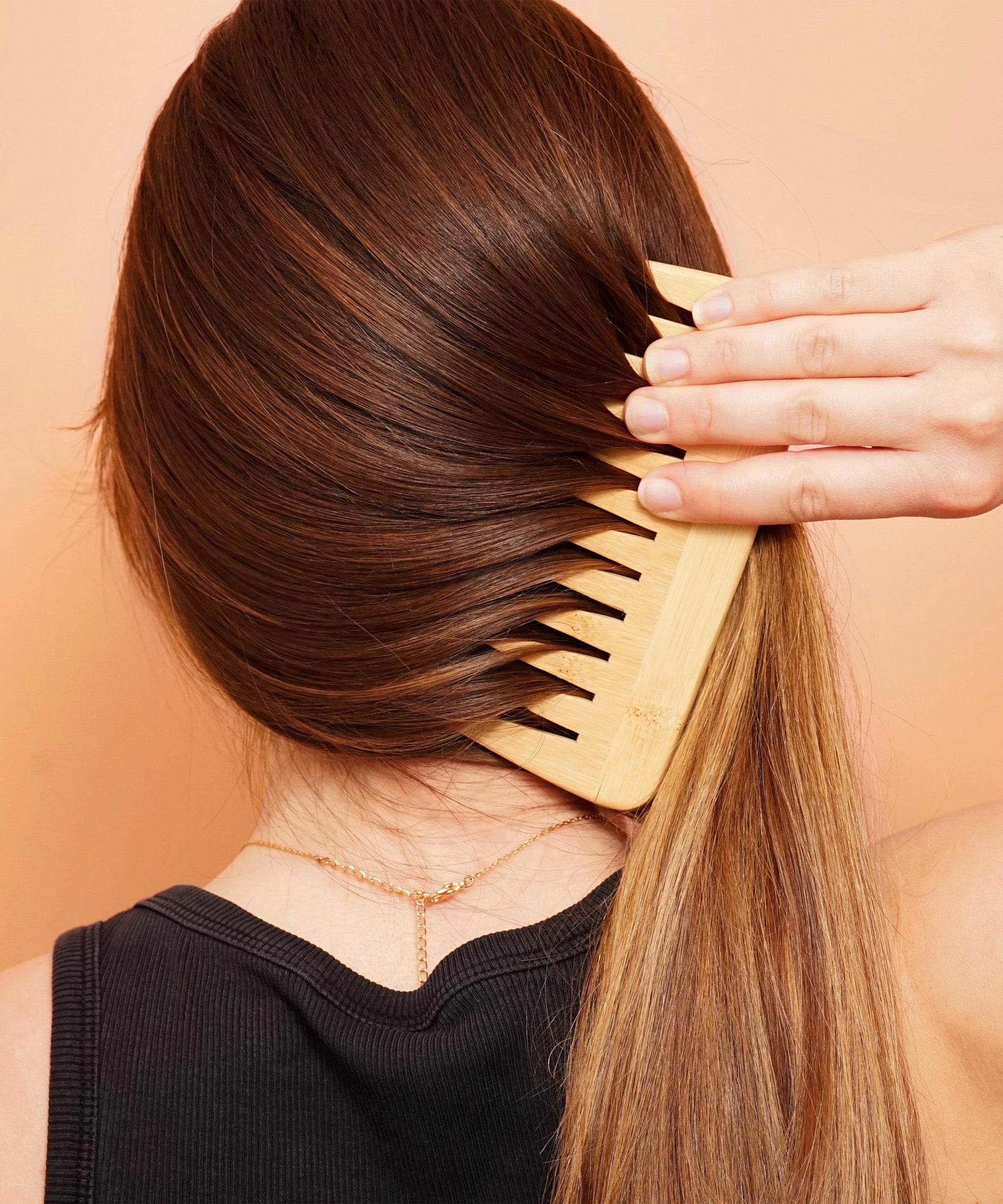 Woman combing long, shiny hair with a wooden comb after using Lamazuna keratin solid haircare for repair and strength.