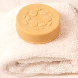 Lamazuna Keratin Repair Solid Shampoo Bar placed on a folded white towel, a round vegan shampoo bar for damaged or dull hair.