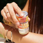 Person applying the Lamazuna Moskito Block natural citronella mosquito repellent stick to their arm, showing the refillable aluminium design and easy glide formula