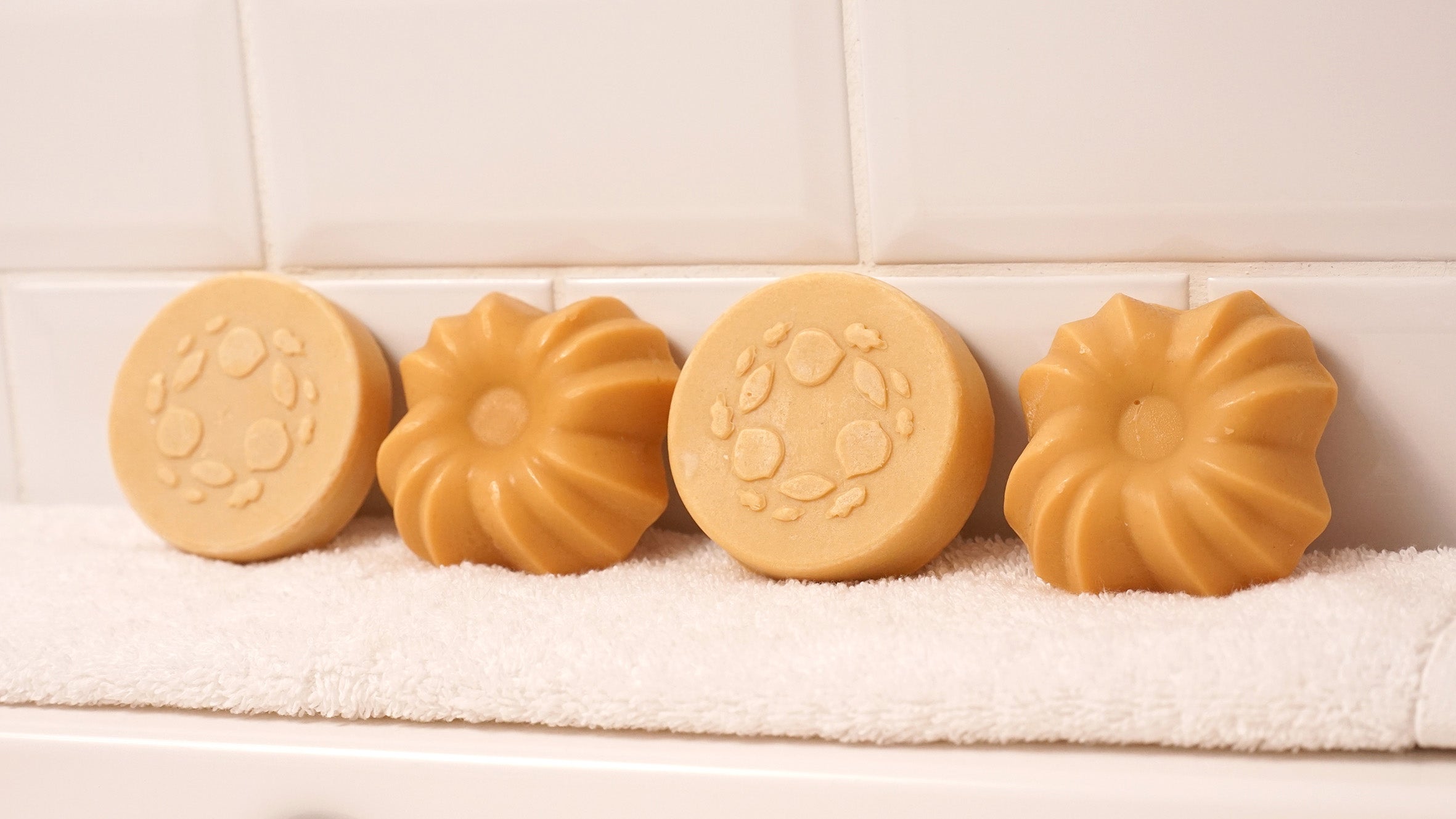 Lamazuna Keratin Repair solid shampoo bar and Keratin Shine solid conditioner bar displayed side by side on a white towel, showing the round shampoo bar and fluted conditioner bar