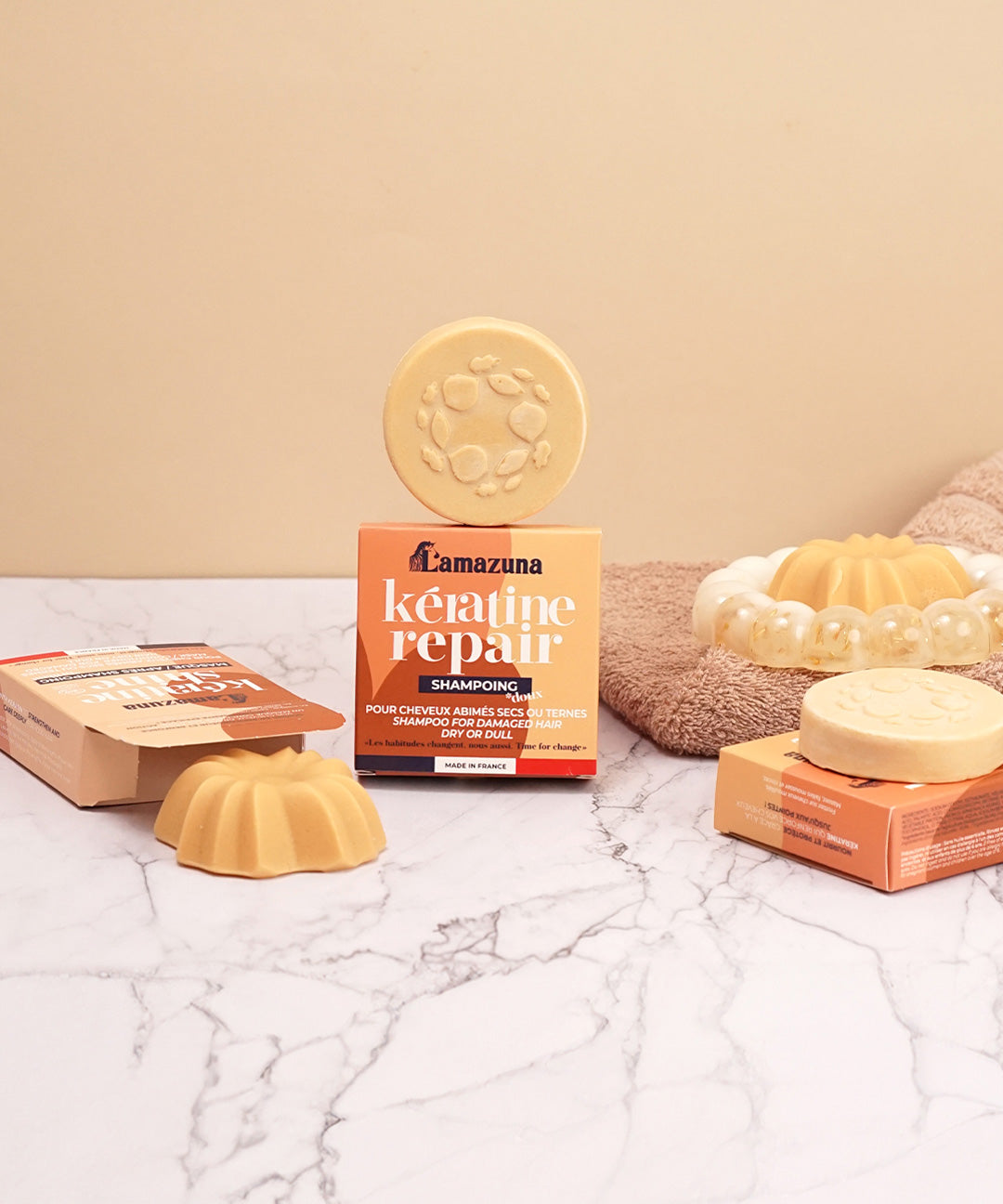 Lamazuna Keratin Repair solid shampoo bar and Keratin Shine conditioner bar arranged with their packaging on a marble bathroom surface.
