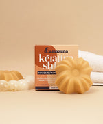 Lamazuna Keratin Shine solid conditioner bar shown in front of its box packaging, styled with bathroom accessories.