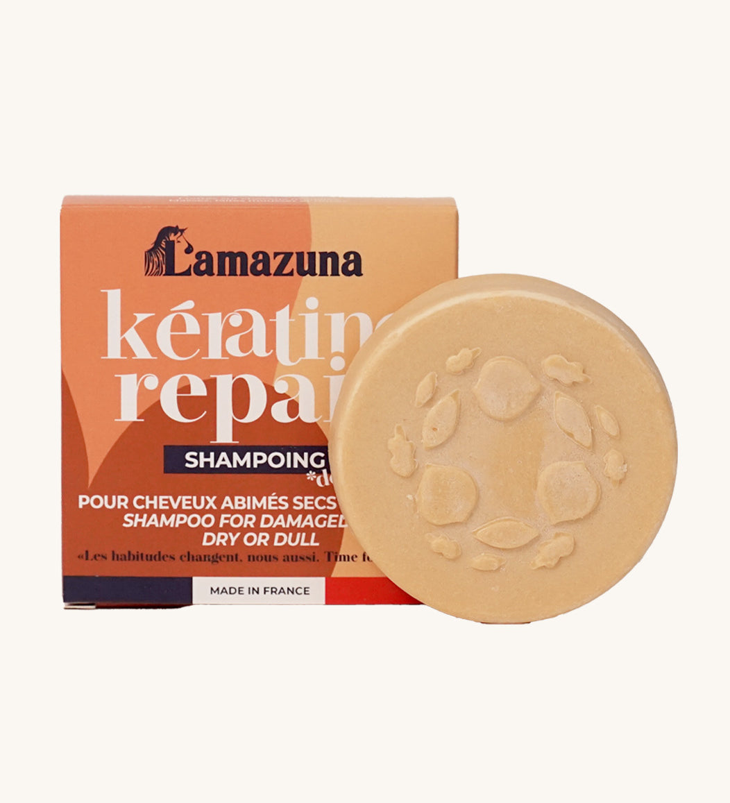 Lamazuna Keratin Repair Solid Shampoo Bar in front of its orange box, a round plant-based keratin shampoo for repairing dry or damaged hair.