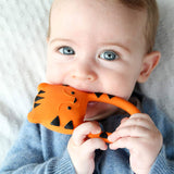 A baby holding and chewing on the Lanco Nalu the Tiger Teether
