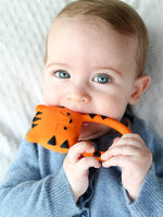 A baby holding and chewing on the Lanco Nalu the Tiger Teether