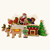 Lanka Kade wooden Christmas play set. 10 toy figures including Father Christmas,  red sleigh, Mrs Clause, Wrapped presents, festive fireplace, Christmas Tree, North Pole Sign, Elf and 2 Reindeer in a cardboard box.