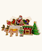 Lanka Kade wooden Christmas play set. 10 toy figures including Father Christmas,  red sleigh, Mrs Clause, Wrapped presents, festive fireplace, Christmas Tree, North Pole Sign, Elf and 2 Reindeer in a cardboard box.