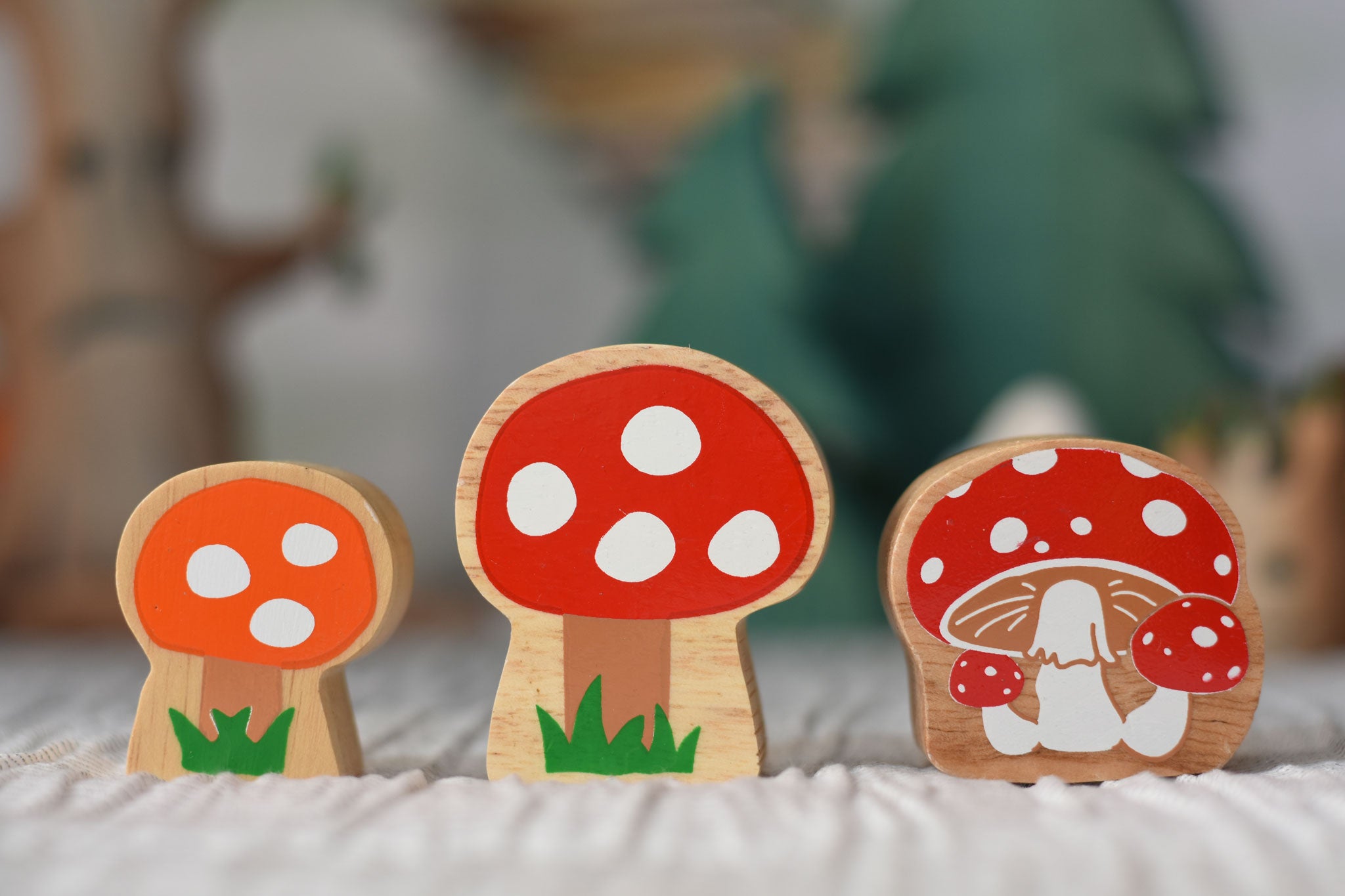 Lanka Kade and Babipur collaboration orange and red spotted toadstool and Lanka Kade Toadstool figures placed on a striped tablecloth. on 