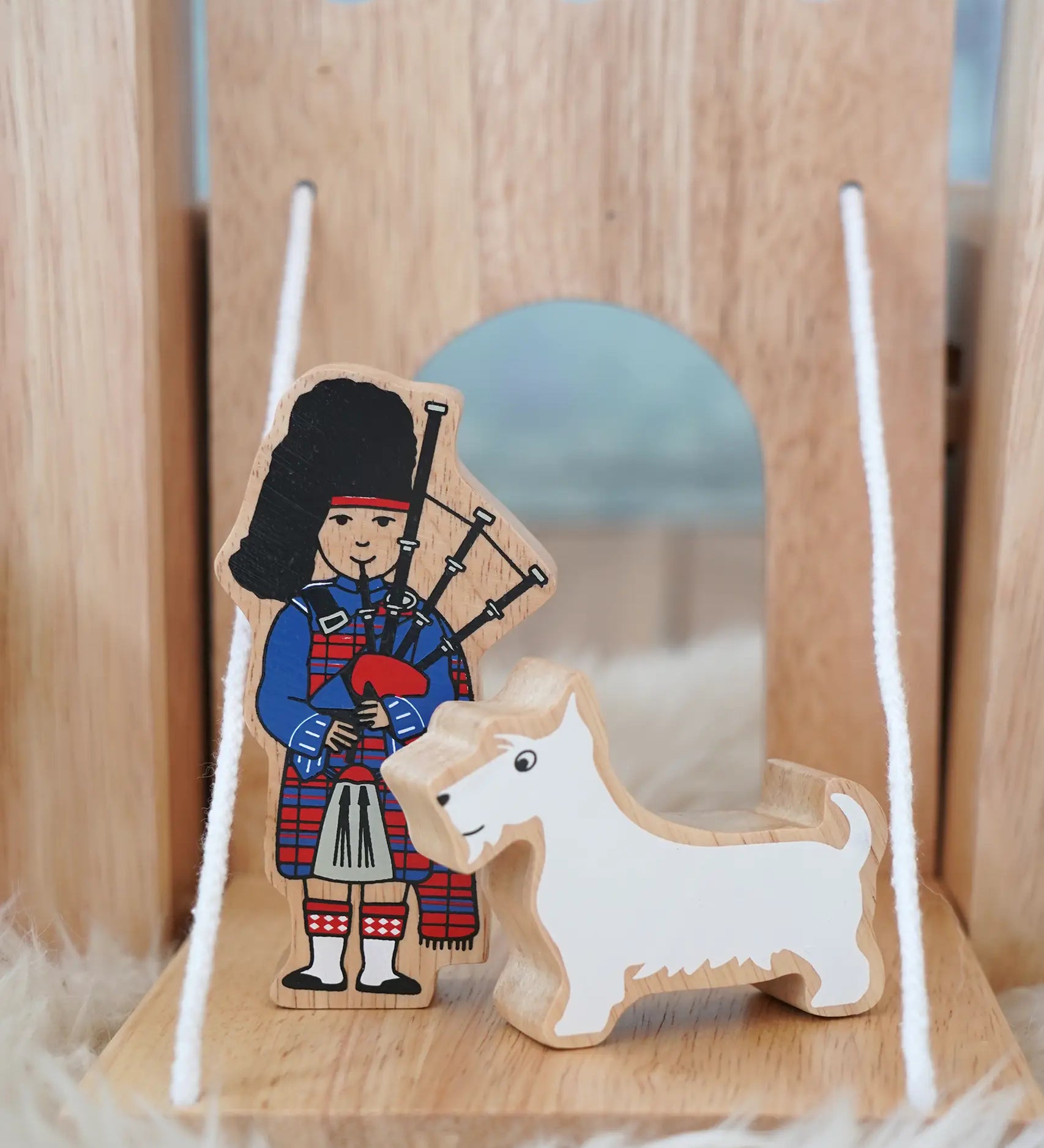 Lanka Kade wooden bagpiper standing next to a white scottie figure on a  castle  drawbridge