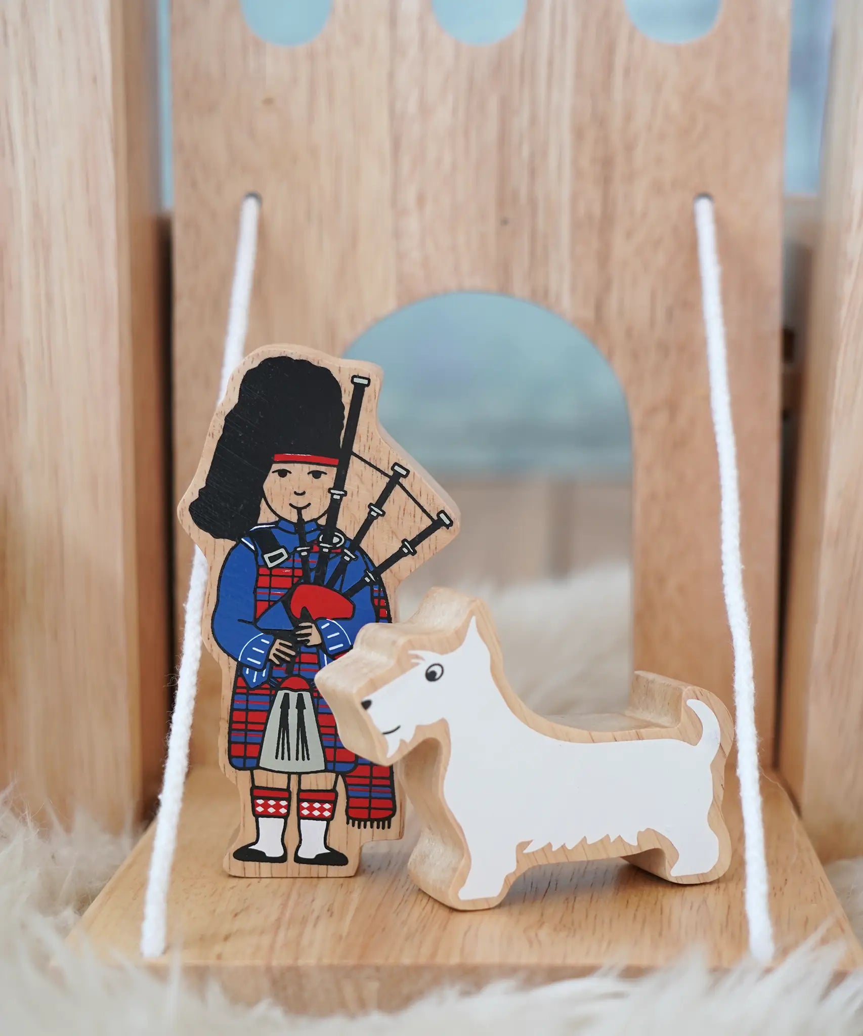 Lanka Kade wooden bagpiper standing next to a white scottie figure on a  castle  drawbridge