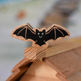 A Lanka Kade wooden toy bat placed on the ridge of the roof of an Osthemer wooden toy cottage. 