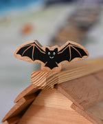 A Lanka Kade wooden toy bat placed on the ridge of the roof of an Osthemer wooden toy cottage. 
