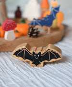A Lanka Kade wooden toy bat placed in front of an Autumnal themed Grimm's celebration themed set up. 