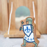 Lanka Kade chunky wooden blue knight figure with morning star weapon standing in front of a wooden castle
