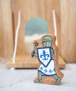 Lanka Kade chunky wooden blue knight figure with morning star weapon standing in front of a wooden castle