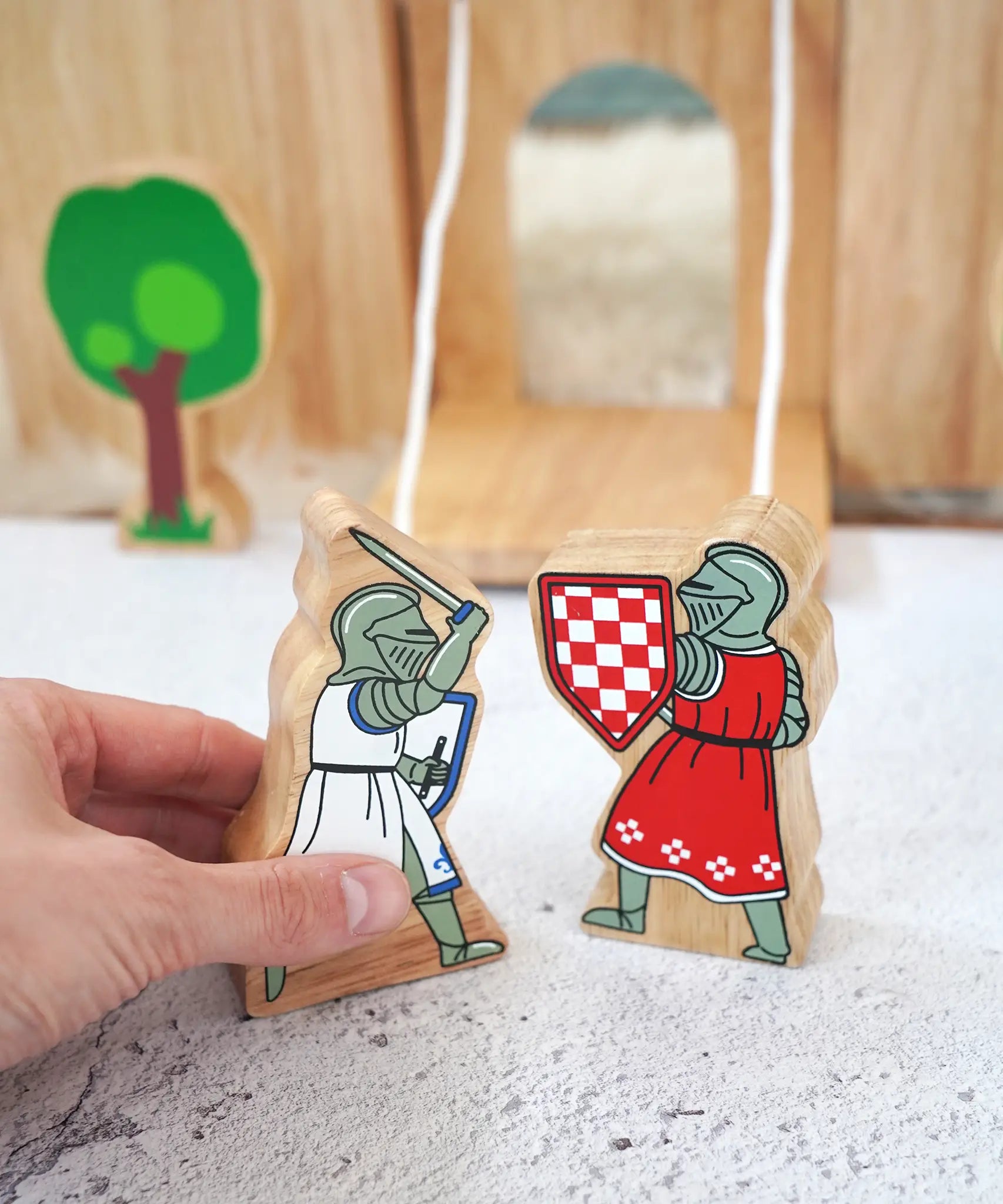 Adult hand holding the Lanka Kade blue knight with raised sword next to a red knight figure showing scale