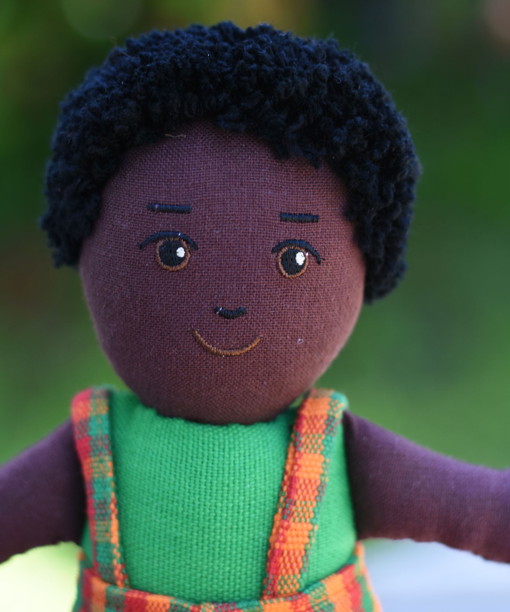 A close up of the face on the Lanka Kade Boy Doll with Black Skin and Black Hair.