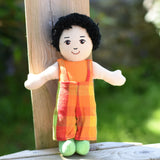 A Lanka Kade Boy Doll with White Skin and Black Hair leaning against a wooden post outdoors.