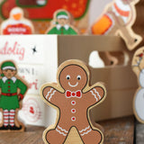 Lanka Kade gingerbread man wooden toy figure placed on a wooden surface in the Babipur playroom with a wooden crate filled with other Christmas figures in the background.