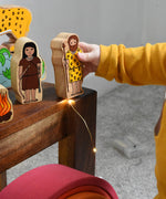 A child holding the cave fan figure from the Lanka Kade Prehistoric Playset. A play set that contains 8 wooden figure and scenery pieces. These wooden toy figures are part of a huge range of Lanka Kade fair trade, wooden toys available here at Babipur.