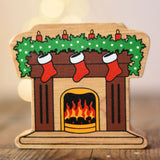 Lanka Kade festive fireplace wooden Christmas wooden toy figure. Brown fireplace with a lit fire, three red stocking hanging with a garland on the mantel decorated with 4 candles. 