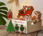Lanka Kade wooden Christmas play set. 9 toy figures including Santa in his sleigh, Mrs Clause, Christmas Tree, Snowman, North Pole Sign, 2 Elves and 2 Reindeer placed in a wooden crate with the Welsh words bocs nadolig on the front.