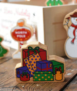 Lanka Kade wrapped presents wooden Christmas wooden toy figure placed on a wooden surface in the Babipur playroom. 