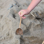 A Lanka Kade coconut rake utensil in a child's hand.