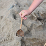 A Lanka Kade coconut rake utensil in a child's hand.