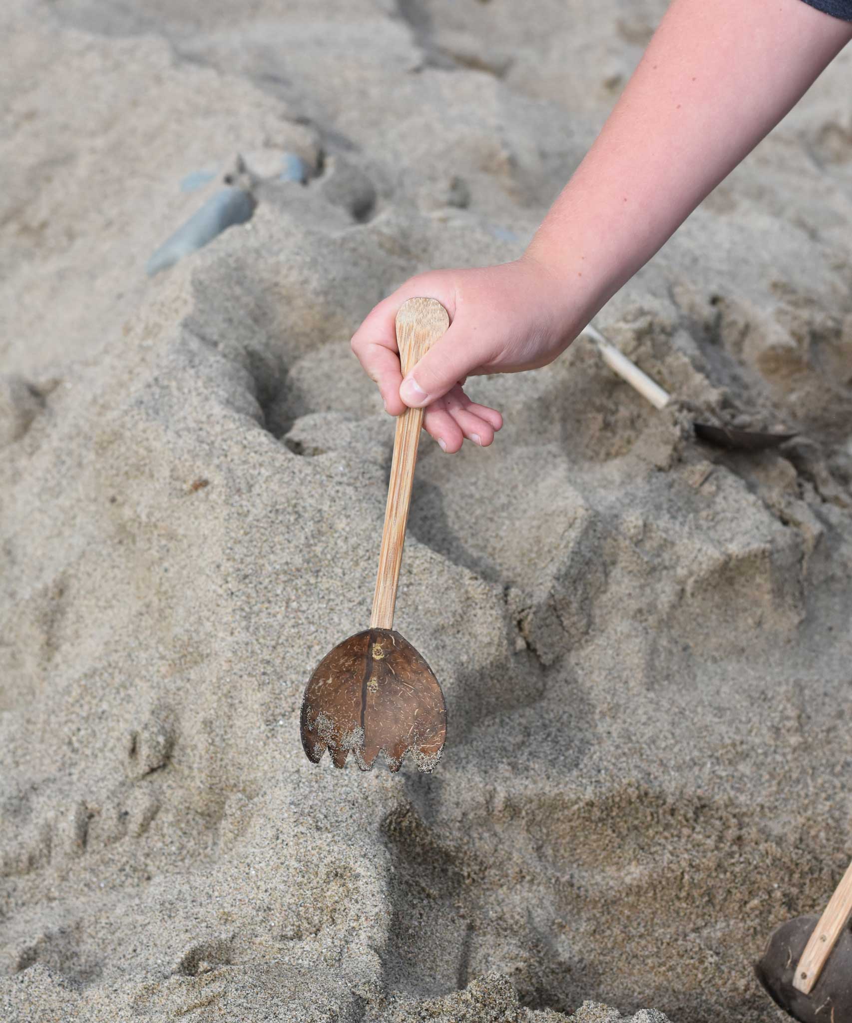 A Lanka Kade coconut rake utensil in a child's hand.
