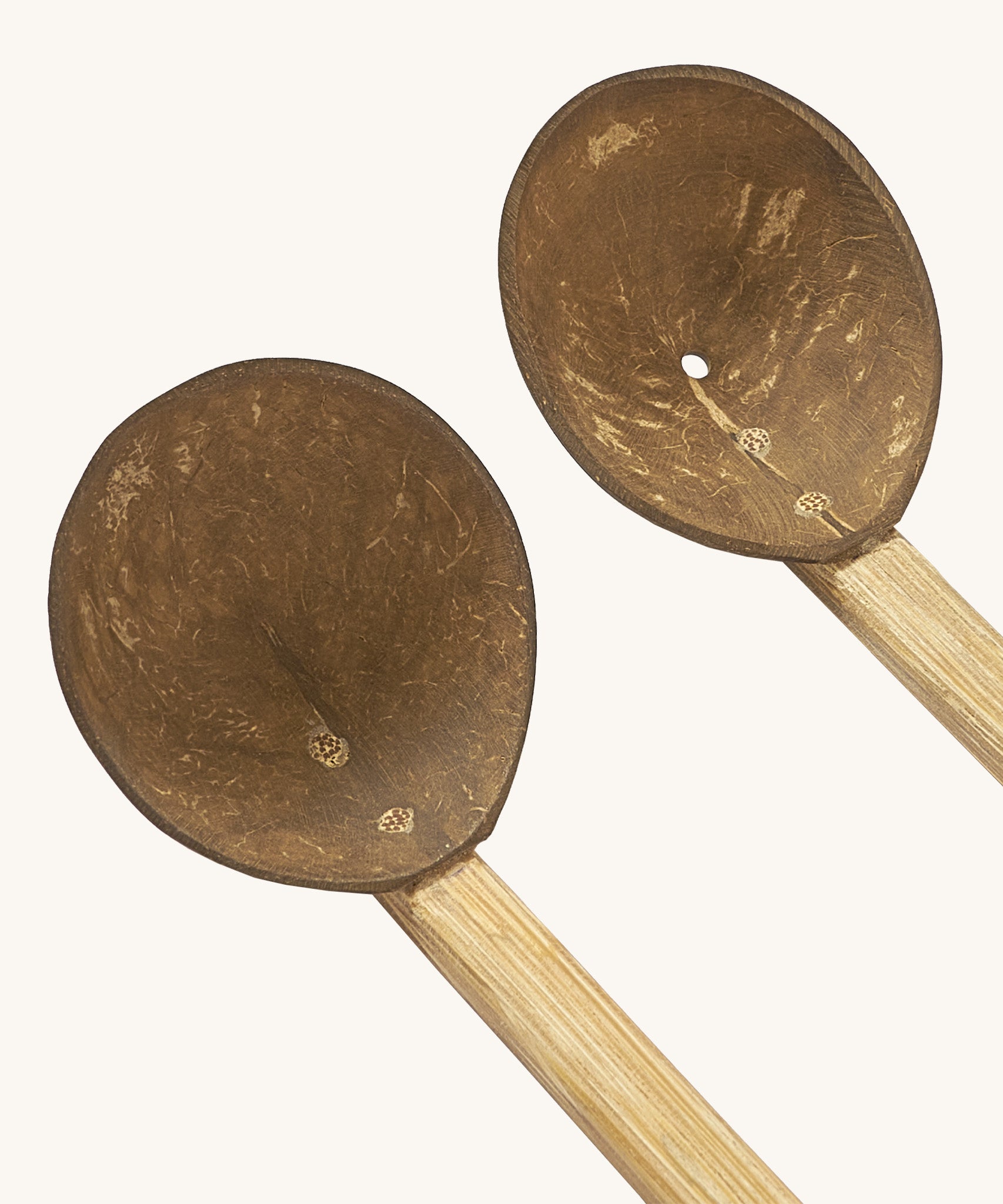 A close up of the 2 Lanka Kade coconut utensils set showing the ladle and colander on wooden handles.