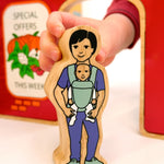A babywearing person from the Lanka Kade community wooden toy figure playset. 