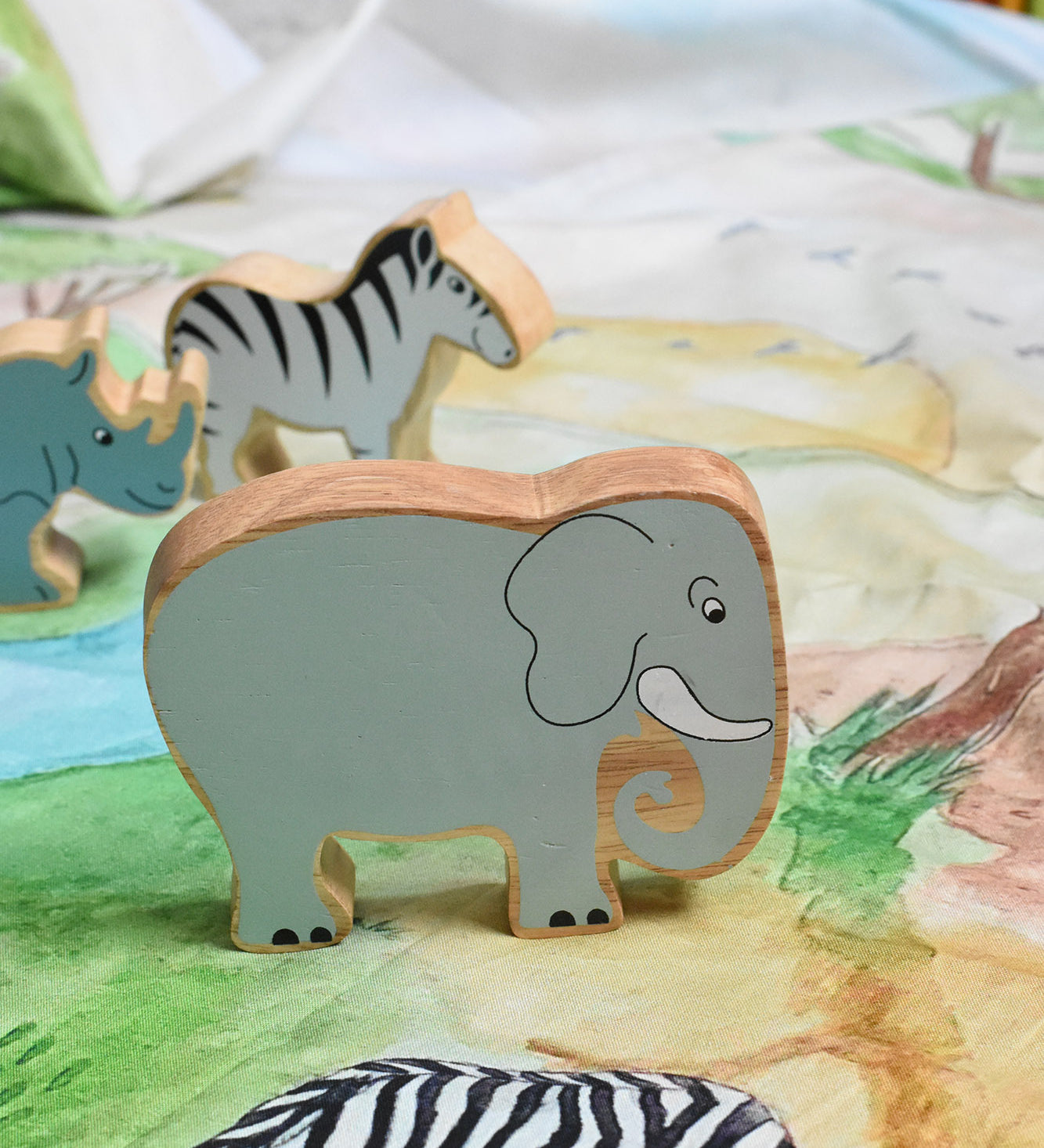 A Lanka Kade grey elephant wooden toy figure placed on a Wonderie plains of Africa play cloth. These wooden toy figures are part of a huge range of Lanka Kade fair trade, wooden toys available here at Babipur.