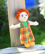 A Lanka Kade Boy Doll with White Skin and Red Hair leaning against a wooden post outdoors.