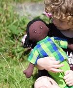 A close up of a Lanka Kade Rag Doll Dad - Black Skin, Black Hair in a child's arms.