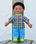 The Lanka Kade dad doll with brown skin and black hair placed on wooden decking. 