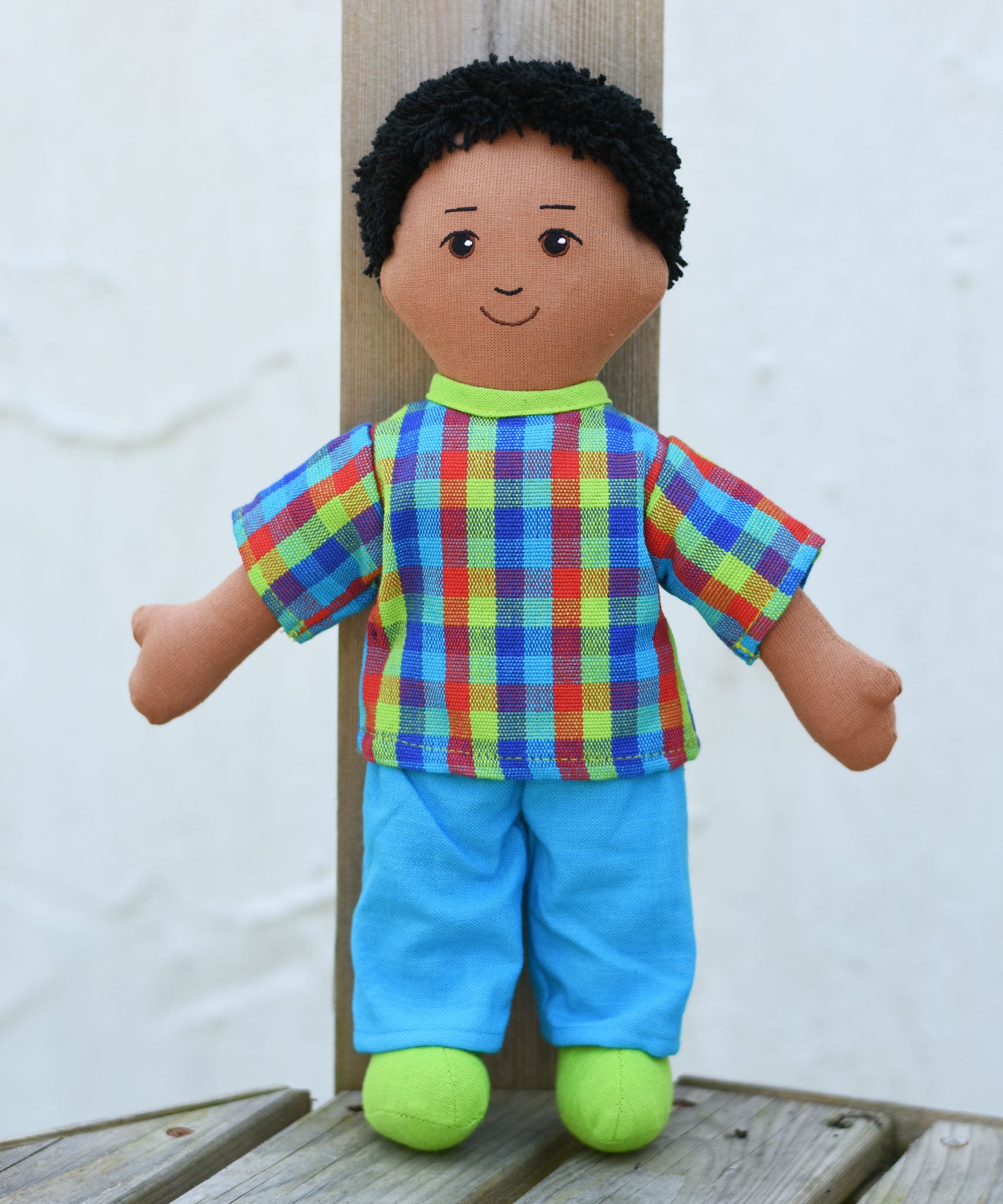 The Lanka Kade dad doll with brown skin and black hair placed on wooden decking. 