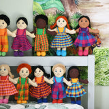 A line up of 10 Lanka Kade Fair Trade boy and girl rag dolls. they have been paced on the pillow and headboard of a bed.