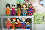A line up of 10 Lanka Kade Fair Trade boy and girl rag dolls. they have been paced on the pillow and headboard of a bed.